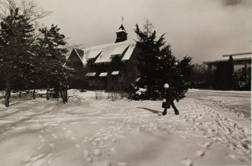 Student walking through snow outside historical Big Red Barn