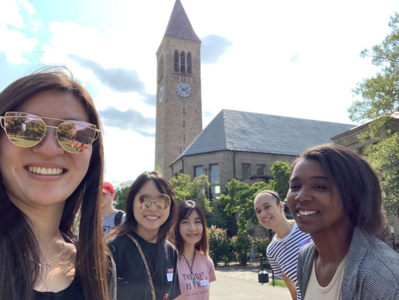 Graduate students take a selfie in front of McGraw Tower